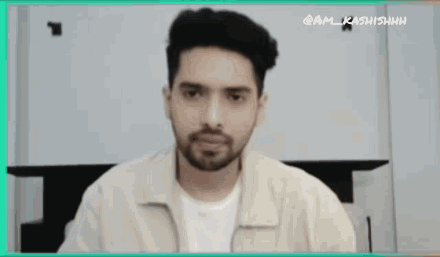 a man with a beard is wearing a white shirt and a tan jacket ..