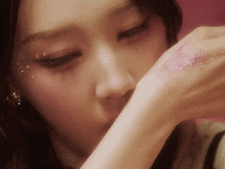 a close up of a woman 's face with glitter on her hand