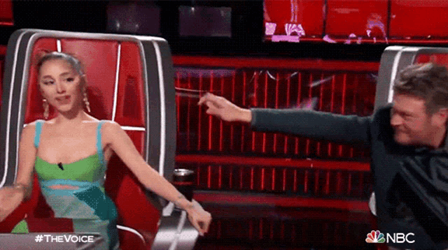 a woman in a green dress is sitting next to a man in a black suit on the voice .