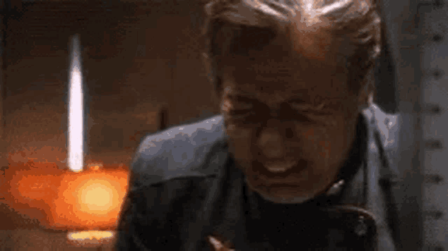 a man is crying in front of a lamp in a room .