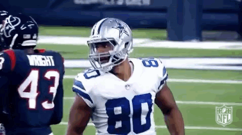 a football player wearing a helmet is talking to another player on a field .