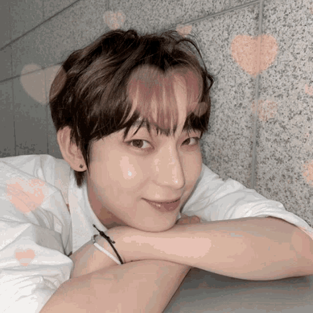 a close up of a young man 's face with pink hearts behind him