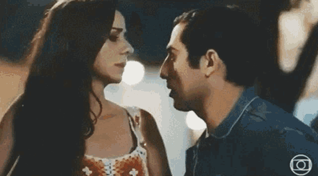 a man and a woman are kissing in front of a logo for globo