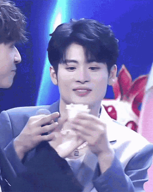 a man in a suit is holding a piece of cake in his hands
