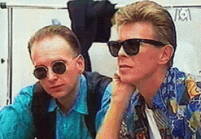 two men wearing sunglasses are sitting next to each other in a room