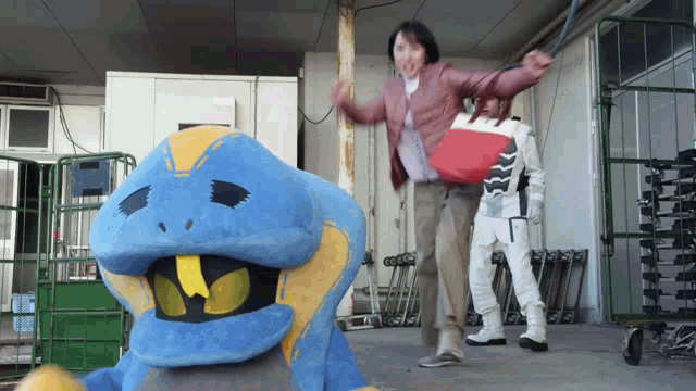 a blue and yellow snake mascot is standing next to a woman