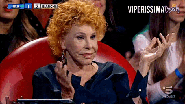 a woman applauds in front of a screen that says blu