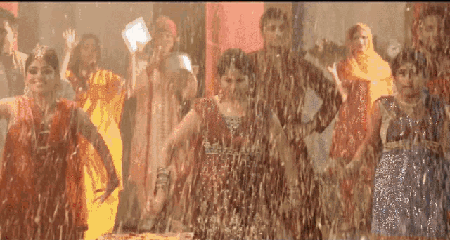 a group of people are dancing in a room with water drops falling on them