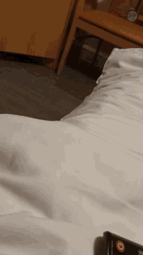 a pillow on a bed next to a remote control that says ' sd ' on it