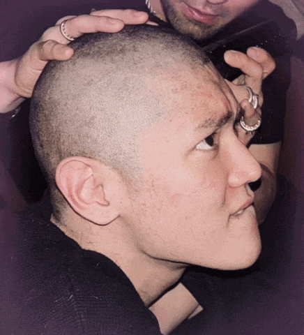 a man with a shaved head has a ring on his finger