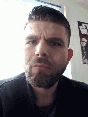 a man with a beard and a star wars poster behind him