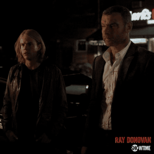 two men are standing next to each other in front of a sign for ray donovan showtime