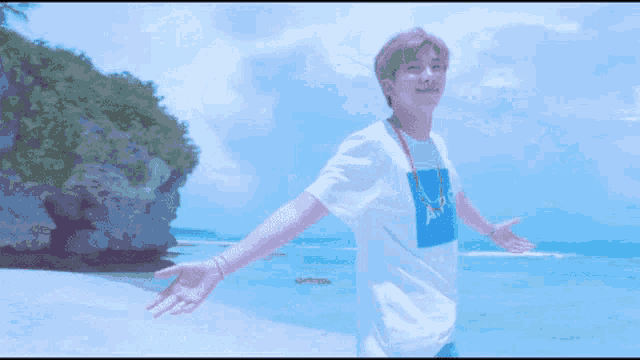 a man is standing on a beach with his arms wide open