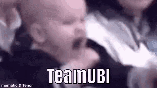 a baby is crying in a man 's arms and the words teamubi are visible .