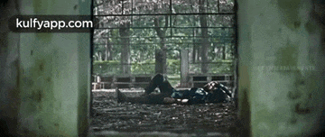 a man is laying on the ground in front of a window with trees in the background .