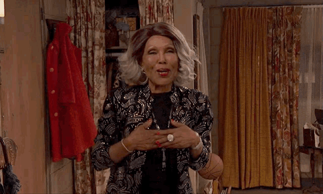 a woman in a sequined jacket is standing in a room with curtains
