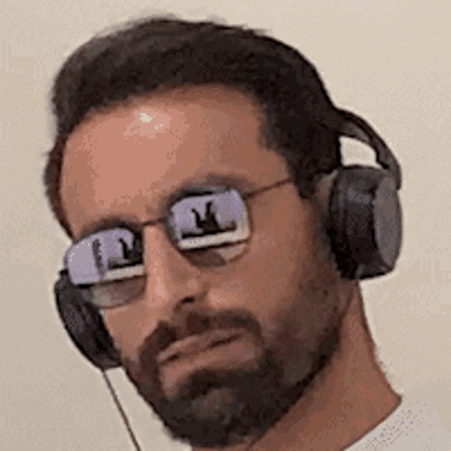 a man with a beard is wearing sunglasses and headphones .
