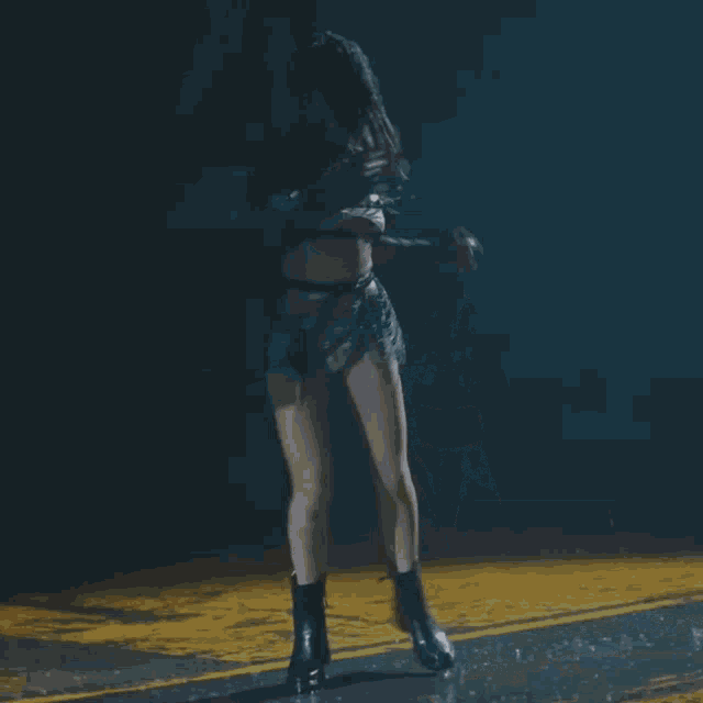 a woman is squatting down in the dark with a yellow line in the background