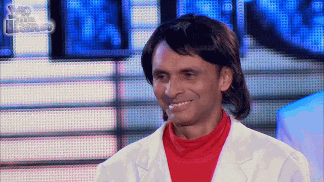 a man in a white coat and red sweater is smiling in front of a sign that says ' 80 's are the best