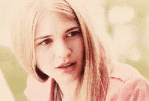 a close up of a blonde woman wearing a pink jacket .