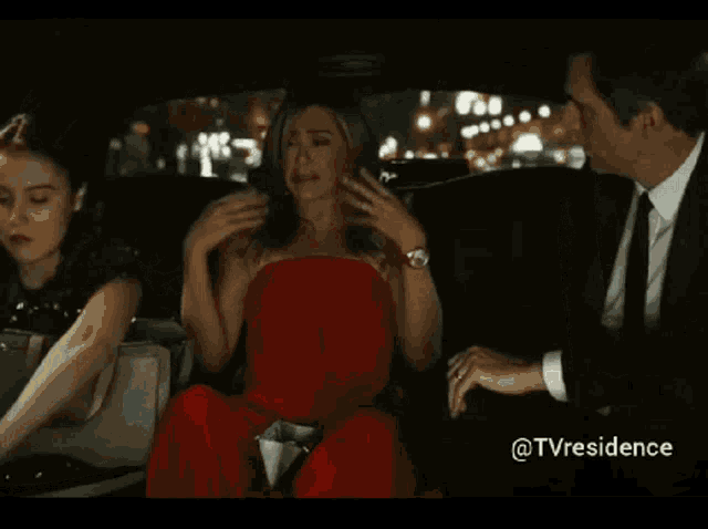 a woman in a red dress is crying in a car while wearing a red watch
