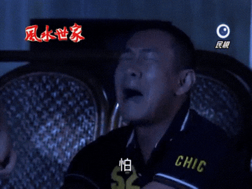a man is crying in front of a sign with chinese writing