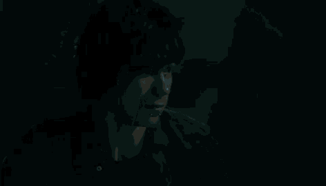a young man is crying in a dark room .
