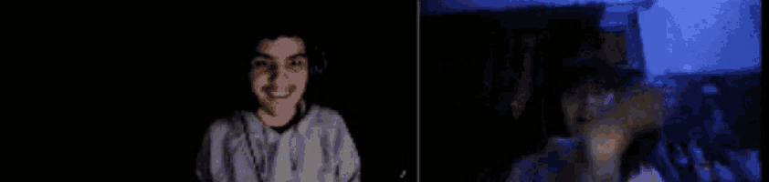 a man in a hoodie is holding a remote control in his hand in a dark room