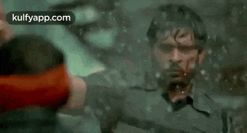a man with blood on his face is standing in the water and looking at the camera .