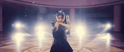 a woman in a black dress is dancing in a room with a lot of lights