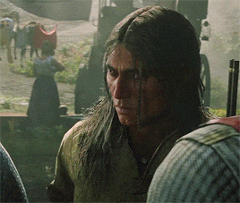 a man with long hair is standing in front of a horse drawn carriage