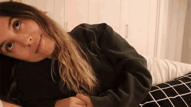 a woman with a nose ring is laying on her stomach