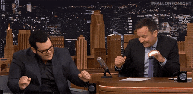 two men in suits and ties are dancing in front of a microphone with the words #fallontonight on the bottom