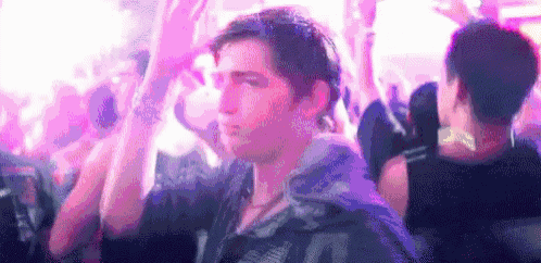 a man is dancing in a crowd of people at a nightclub .
