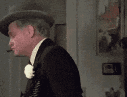a man in a suit and top hat smoking a cigar .
