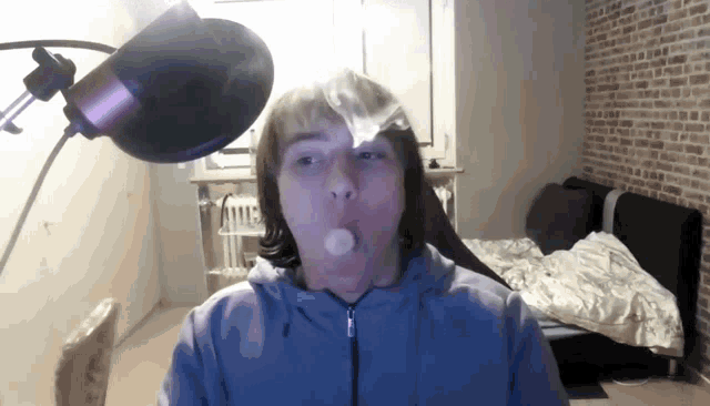 a man blowing bubbles in front of a microphone in a bedroom