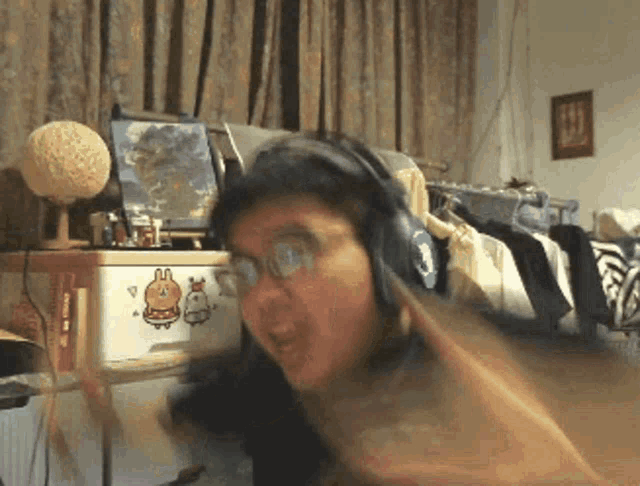 a person wearing headphones and glasses is standing in front of a computer monitor