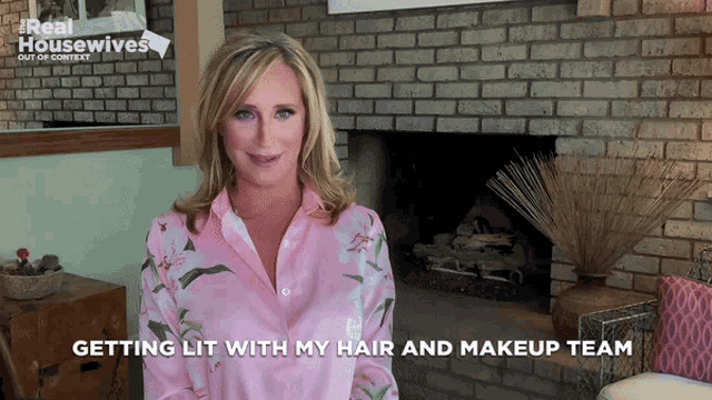 a woman in a pink shirt with the words getting lit with my hair and makeup team below her