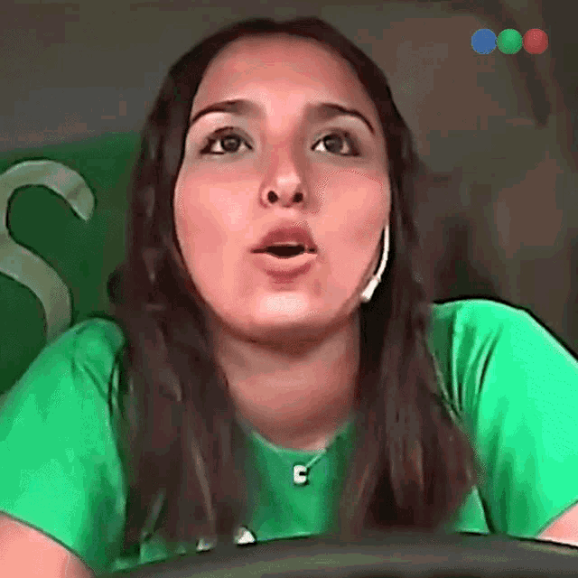 a woman wearing a green shirt with the letter c on her neck