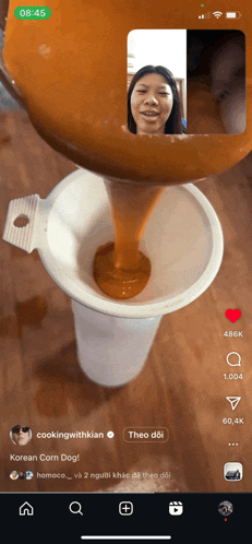 a phone screen shows a video of a woman pouring sauce into a cone