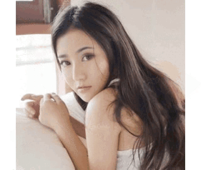 a woman is laying on a bed with her head on a pillow .