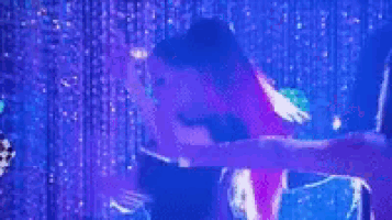 a group of women are dancing on a stage in front of a crowd .