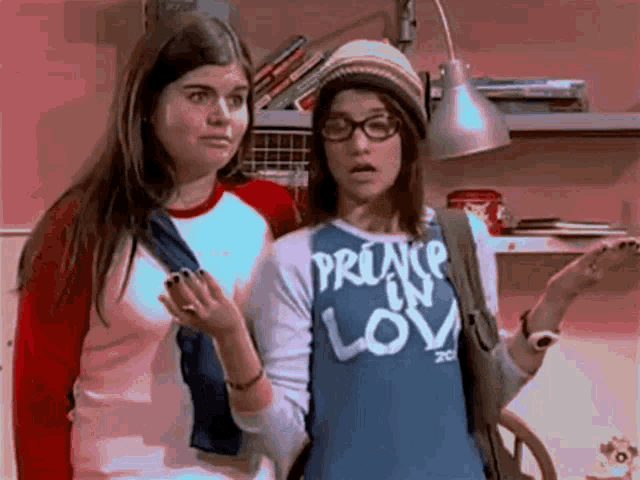 a girl wearing a shirt that says prince in love stands next to another girl