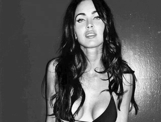 a black and white photo of a woman in a plunging black top