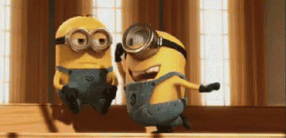 two minions are standing next to each other on a table .