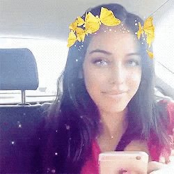 a woman wearing a flower crown is sitting in a car holding a cell phone
