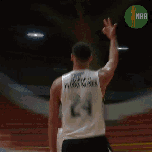 a basketball player throws a ball with a nbb logo behind him