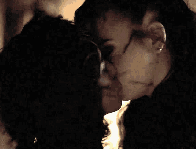 two women kissing in a dark room with a light behind them