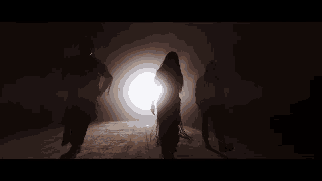 a group of people standing in the dark with a light behind them