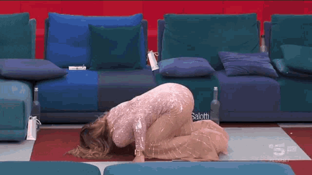a woman in a sequined dress is kneeling down in front of a couch with the word salotti on it